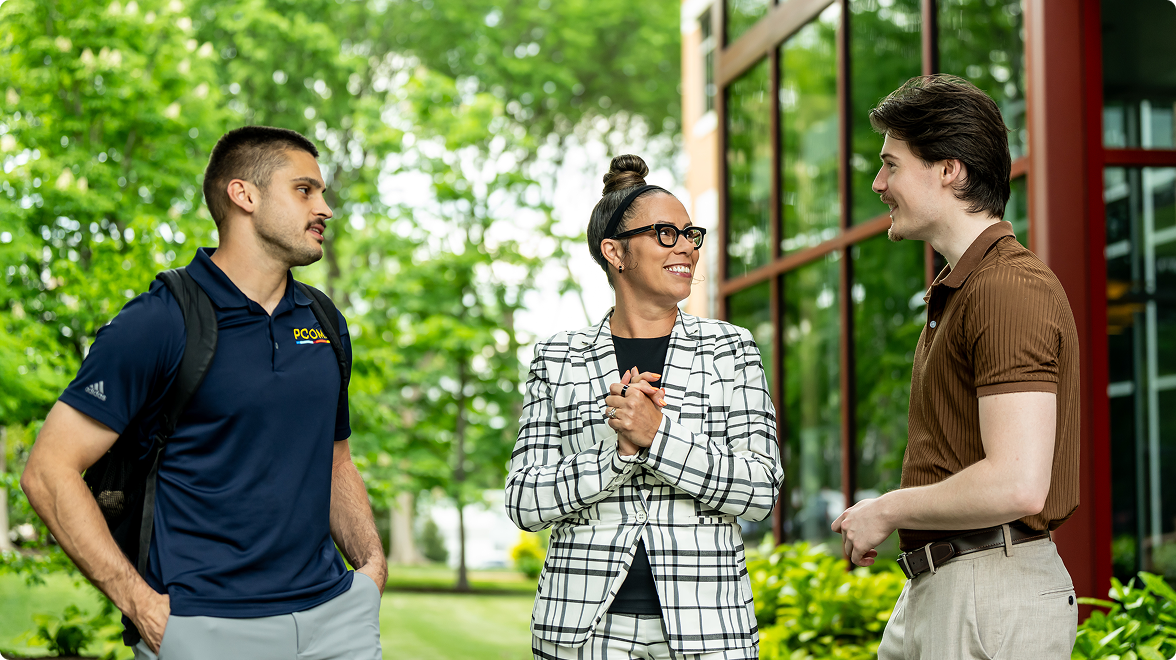 faculty member of PCOM talking with two students on campus