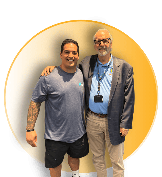Zach Murphy posing with a faculty member in a blazer and PCOM lanyard inside a circular frame with a gold accent border