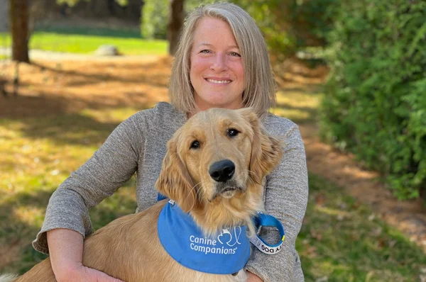 tracey ransom holding golden retriever in outdoor landscape